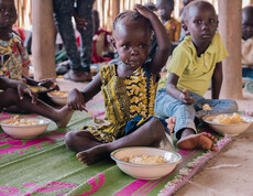 Südsudanesische Kinder sitzen am Boden und essen