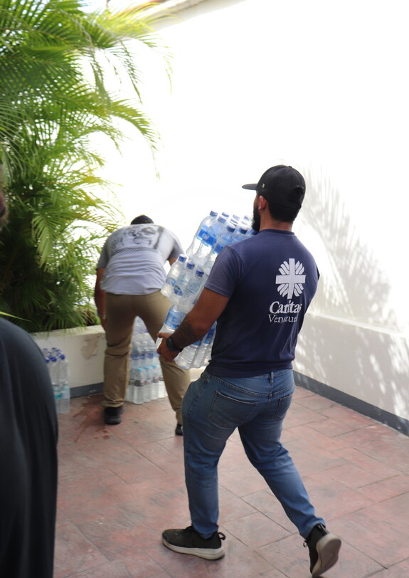 Caritas-Helfer trägt Trinkwasser für Menschen nach dem Erdbeben in Venezuela.