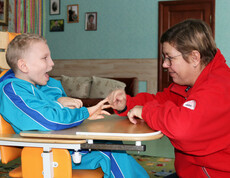 Eine Betreuerin spielt mit einem Kind im Kinderdorf Gomel und unterstützt es bei einer interaktiven Aktivität.