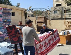 Helfer*innen übergeben Matratzen an Betroffene in einem offenen Hof in Gaza.