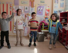 Sechs Kinder machen eine koordinierte Gruppenübung in einem bunt dekorierten Klassenraum im Libanon