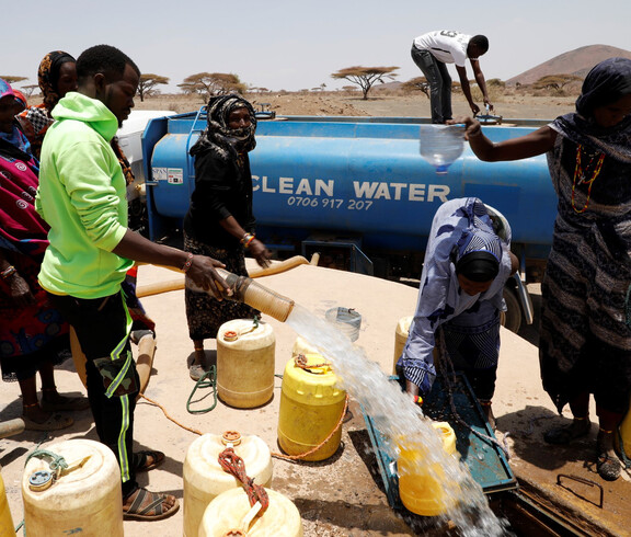 Afrikanische Menschen stehen vor einem Brunnen und füllen gelbe Kanister mit frischem Trinkwasser.