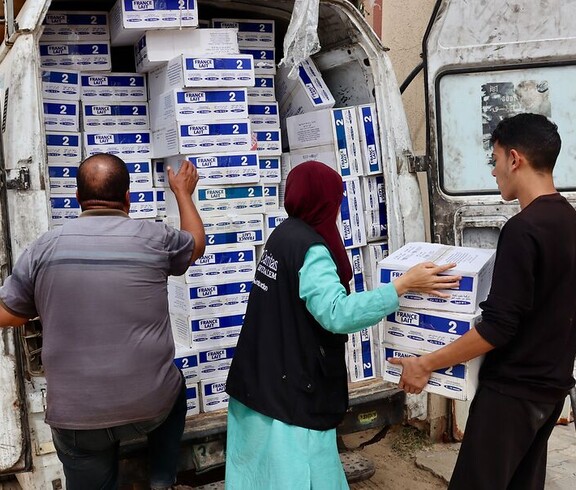 Mehrere Helfer*innen der Caritas Jerusalem laden Kisten mit Babynahrung aus einem Transporter. Der Wagen ist mit Hilfspaketen voll beladen.