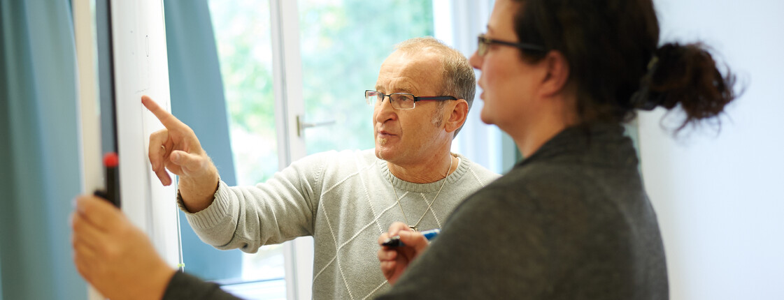 Bildungsreferent zeigt auf Flipchart