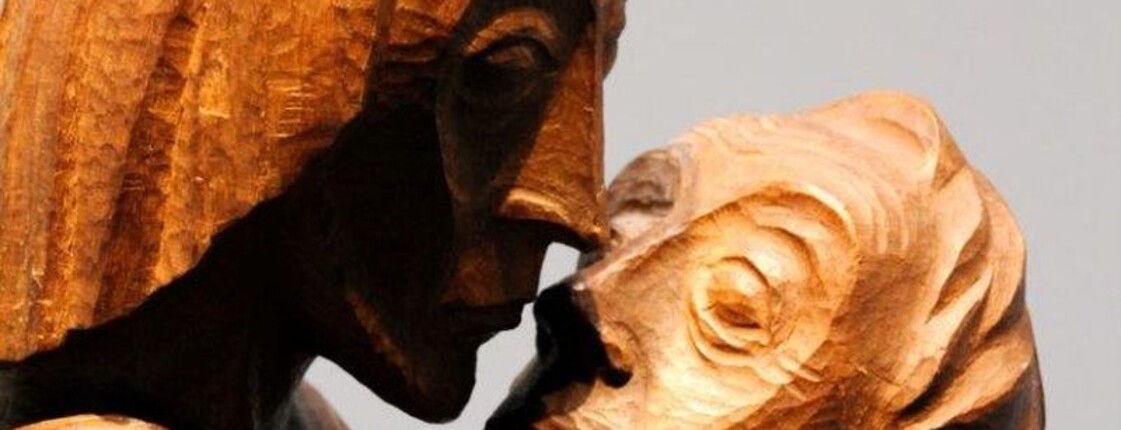 Eine Holzstatue, zwei Männer umarmen sich.