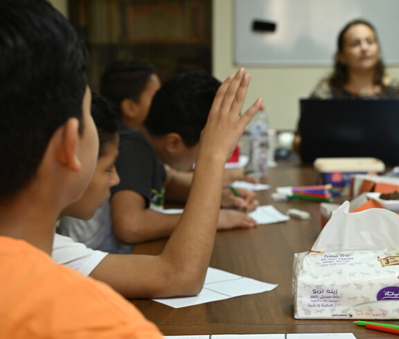 In Straßenkinderzentrum erhalten die Kinder einen Basisunterricht von geschulten Betreuerinnen.  Kinder werden in einer Klasse unterrichtet und heben die Hand.