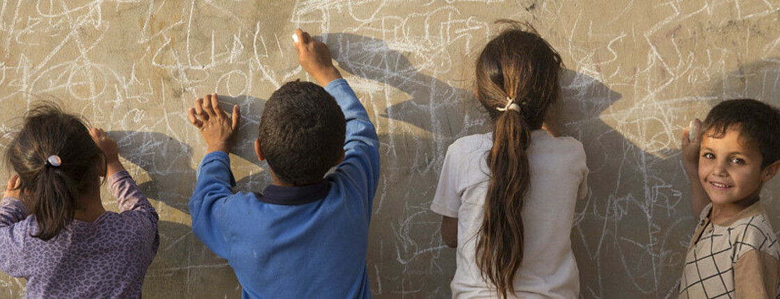 Kinder beim Schreiben mit Kreide auf einer Wand