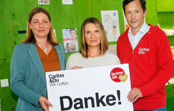 Nora Tödtling-Musenbichler, Barbara Stöckl und Klaus Schwertner (von links nach rechts) halten gemeinsam ein großes Dankesschild der Hilfsorganisation Caritas in die Kamera.