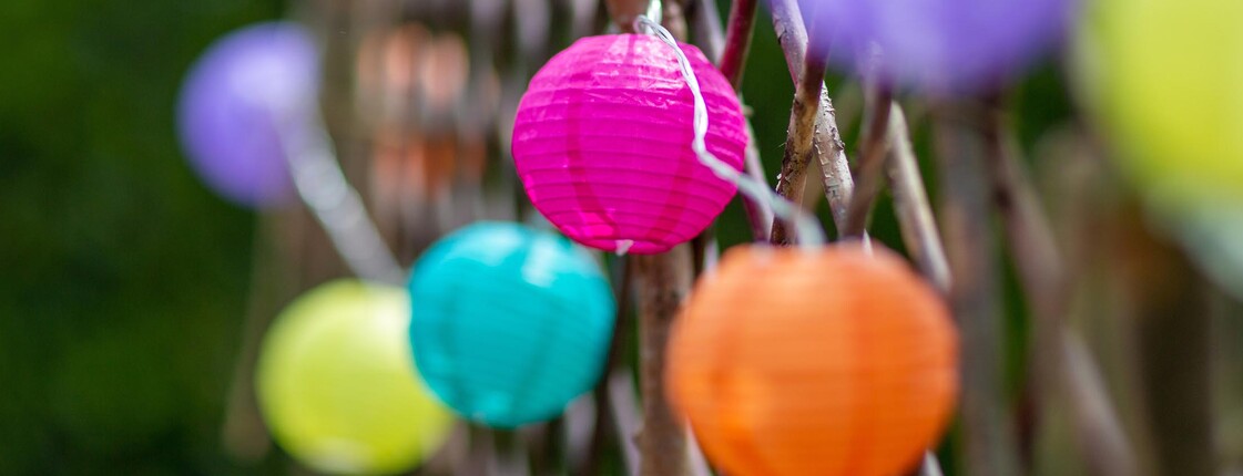 Bunte Lampion-Lichterkette auf Holzzaun