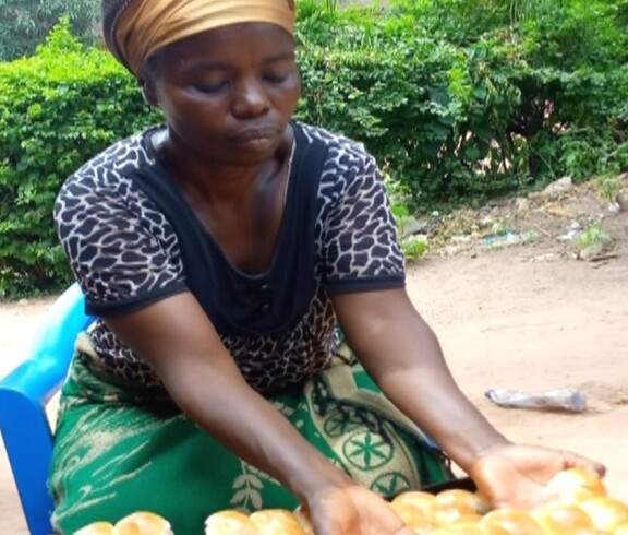Person sitzt im Freien und hält mehrere Lebensmittelstücke in den Händen, Fokus auf Versorgung mit Nahrung