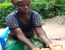 Person sitzt im Freien und hält mehrere Lebensmittelstücke in den Händen, Fokus auf Versorgung mit Nahrung