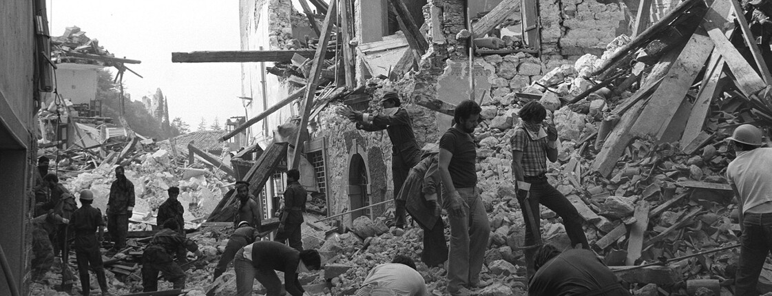 Menschen räumen Trümmer zwischen eingestürzten Gebäuden nach dem Erdbeben 1976 in Friaul, Schwarzweißaufnahme