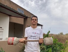 Eine Person steht im Freien und hält selbstgebaute Hanteln in den Händen.