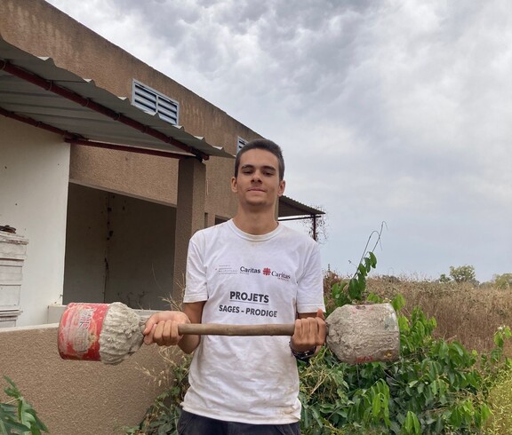 Eine Person steht im Freien und hält selbstgebaute Hanteln in den Händen.