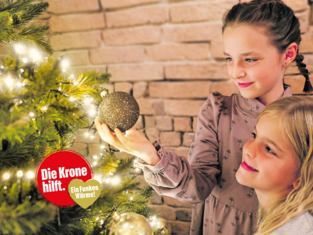 Zwei Mädchen beim Christbaum - und ein Logo "Die Krone hilft. Ein Funken Wärme"