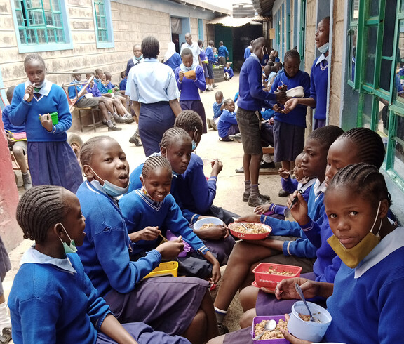 Schüler*innen sitzen im Innenhof der Schule und genießen das Mittagessen.