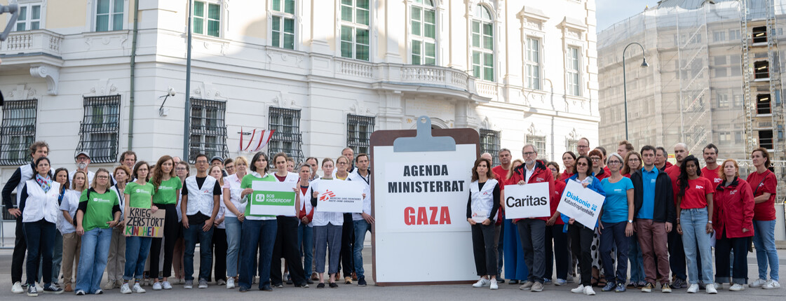 Österreichische Hilfsorganisationen stehen mit einem großen Klemmbrett vor dem Bundeskanzleramt