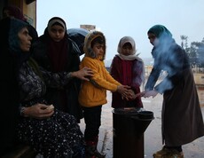 Kinder und Frauen stehen um eine Wärmestelle herum