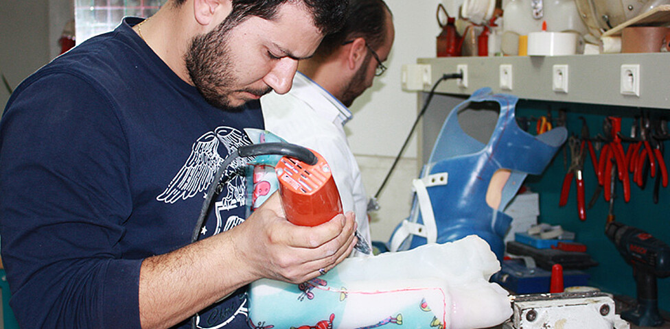 Zwei Mitarbeiter der Orthopädischen Werkstatt in Damaskus bei der Arbeit an einer Prothese für syrische Kriegsversehrte.