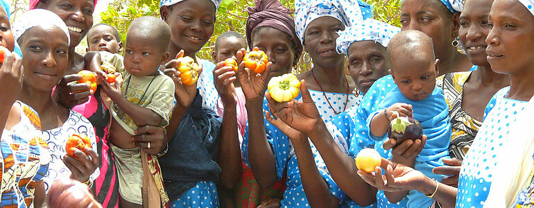 Gruppe von Frauen und kleinen Kindern halten Gemüse in den den Händen