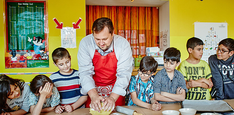 Caritasdirektor Hannes Zieselsberger mit einer Gruppe von Kindern beim Keksebacken