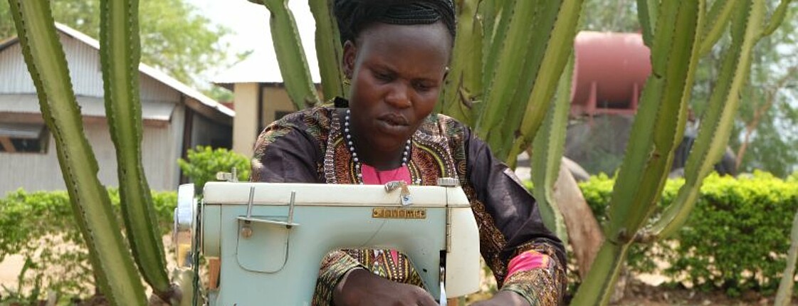 Eine afrikanische Frau näht an einer Nähmaschine
