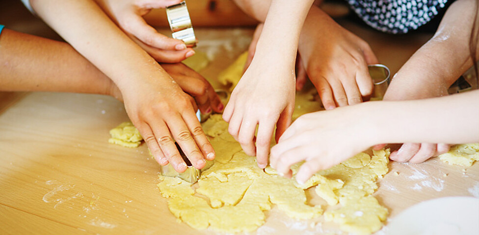 Kinder stechen Kekse aus einem Teig aus