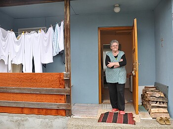 Ein ältere Frau steht am Eingang ihres Hauses.