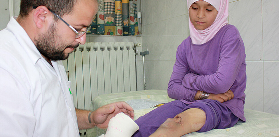 Ein Arzt passt bei einem kriegsversehrten Mädchen eine Beinprothese an.