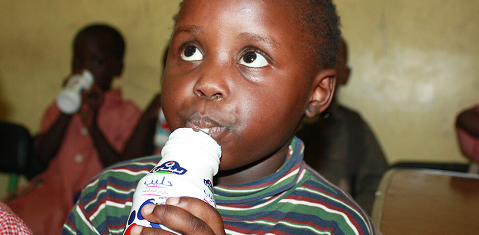 Ein sudanesisches Flüchtlingskind in Kairo trinkt seine Schulmilch.