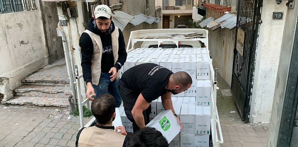 Mitarbeiter*innen der Caritas verladen Hilfsgüter für die Menschen in Syrien