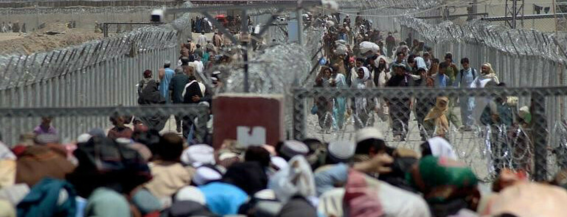 Menschenmassen stehen vor einem Drahtzaun an der Grenze Afghanistans