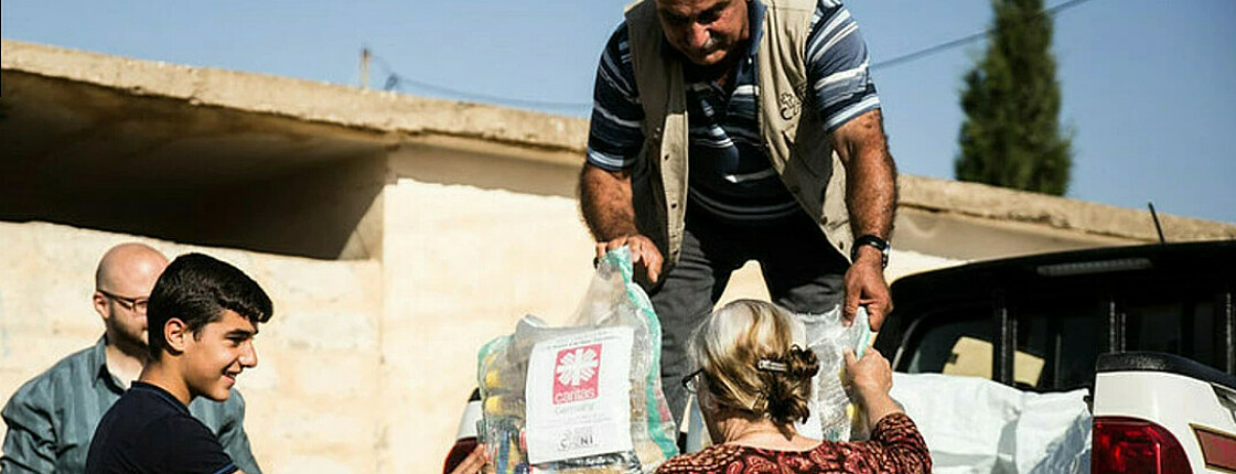 Helfer der Caritas Syrien laden Hilfspakete aus