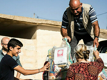 Helfer der Caritas Syrien laden Hilfspakete aus