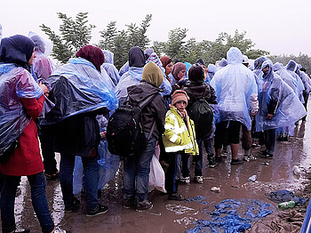 Flüchtlinge in Regenmänteln an der Grenze