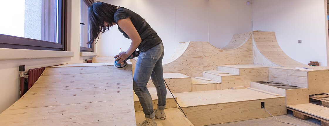 Eine junge Frau arbeitet an Holzverkleidungen in einem Zimmer