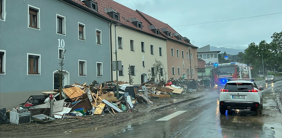 Eine Straße, am Rand liegen von den Wassermassen mitgerissene und zerstörte Gegenstände