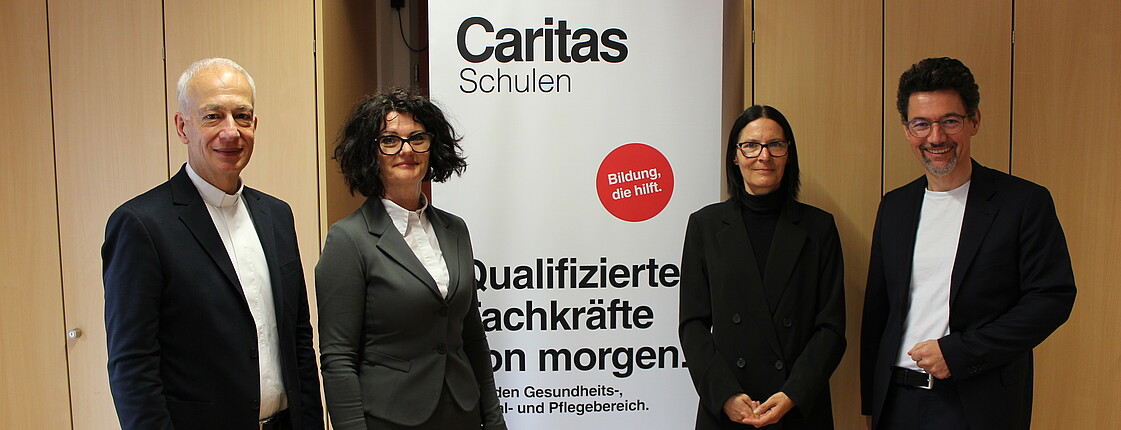 (v.l.n.r.) Michael Landau, Manuela Kröll, Birgit Poier und Ernst Sandrießer stehen vor einem Caritas-Roll Up.