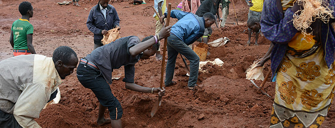 Eine Gruppe von Menschen in Afrika gräbt ein Regenwasser-Sammelbecken.