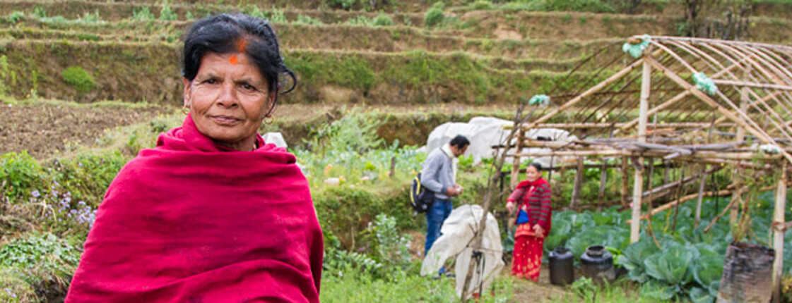Das Bild zeigt eine Kleinbäuerin aus Südasien auf einem Feld stehend