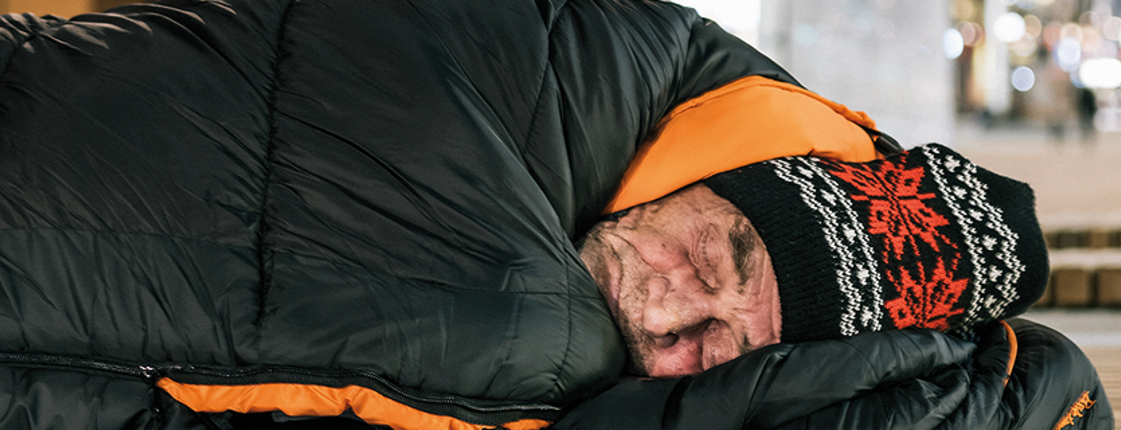 Obdachloser Mann, welcher in einem Schlafsack liegt