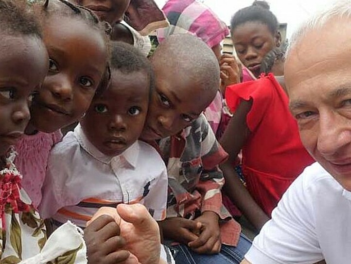 Caritas-Präsident Michael Landau gibt einem kleinen Mädchen die Hand, im Hintergrund Kinder